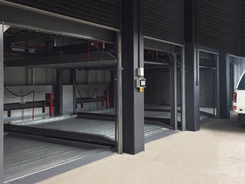 Three open roller doors and a newly installed car stacker in a charcoal coloured garage