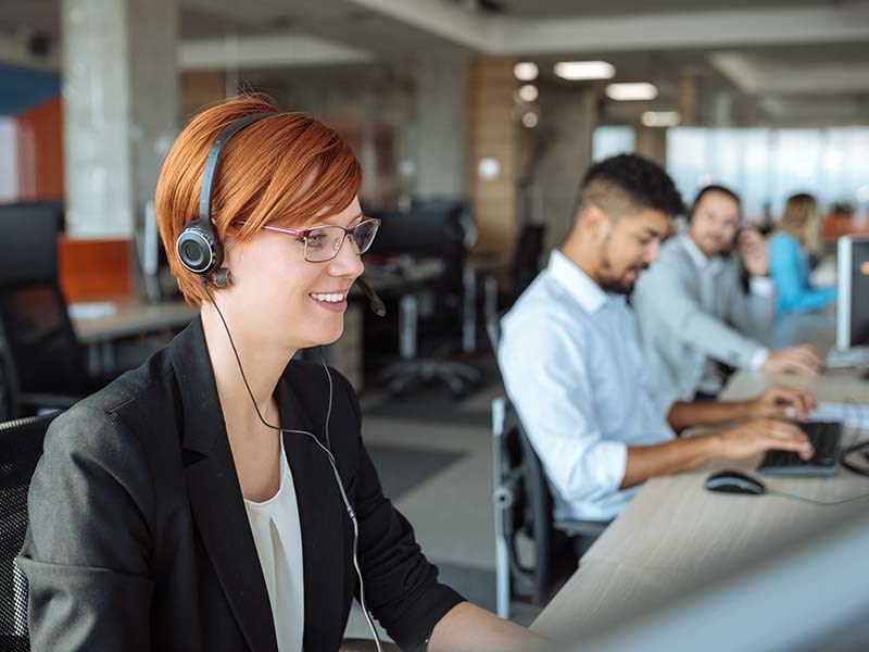 Friendly call-centre girl with red hair wearing headset